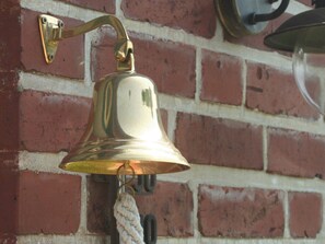A brass bell mounted on a brick wall. - "luv" in House Smaswai 10 (Nebel)