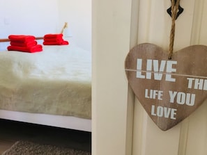 A bedroom with a bed, a red towel, and a wooden heart-shaped sign with the text "LIVE THE LIFE YOU LOVE". - Ostbake Modern Retreat (Wangerooge)