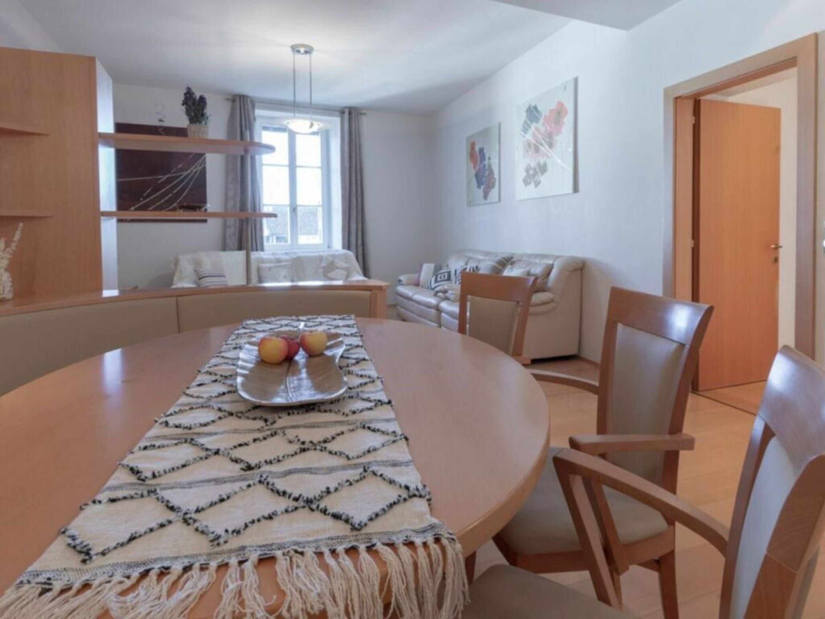 Un comedor con una mesa redonda, sillas y un mantel decorativo.