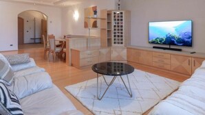 A modern living room with a sofa, a coffee table, a TV, and a dining area. - Perwanger Modern Retreat (Appiano Sulla Strada del Vino)