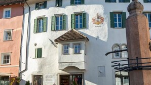A building with a white facade, green shutters, and a coat of arms. - Perwanger Modern Retreat (Appiano Sulla Strada del Vino)