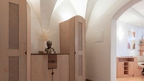 A modern interior with wooden cabinetry, a vase with dried flowers, and a tiled floor. - Perwanger Modern Retreat (Appiano Sulla Strada del Vino)