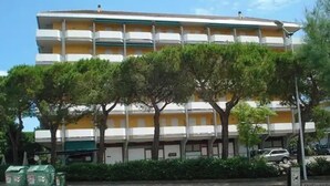 Un immeuble à plusieurs étages doté de balcons, entouré d’arbres et de verdure.