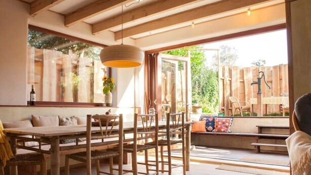 A spacious dining area with wooden furniture and large windows allowing natural light. - Holiday Home Ecolodge The Pearl (Schoorl)