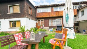 A patio with a wooden table and benches, surrounded by a well-maintained lawn. - Idyllic Apartment in Sibratsgfall (Sibratsgfaell)