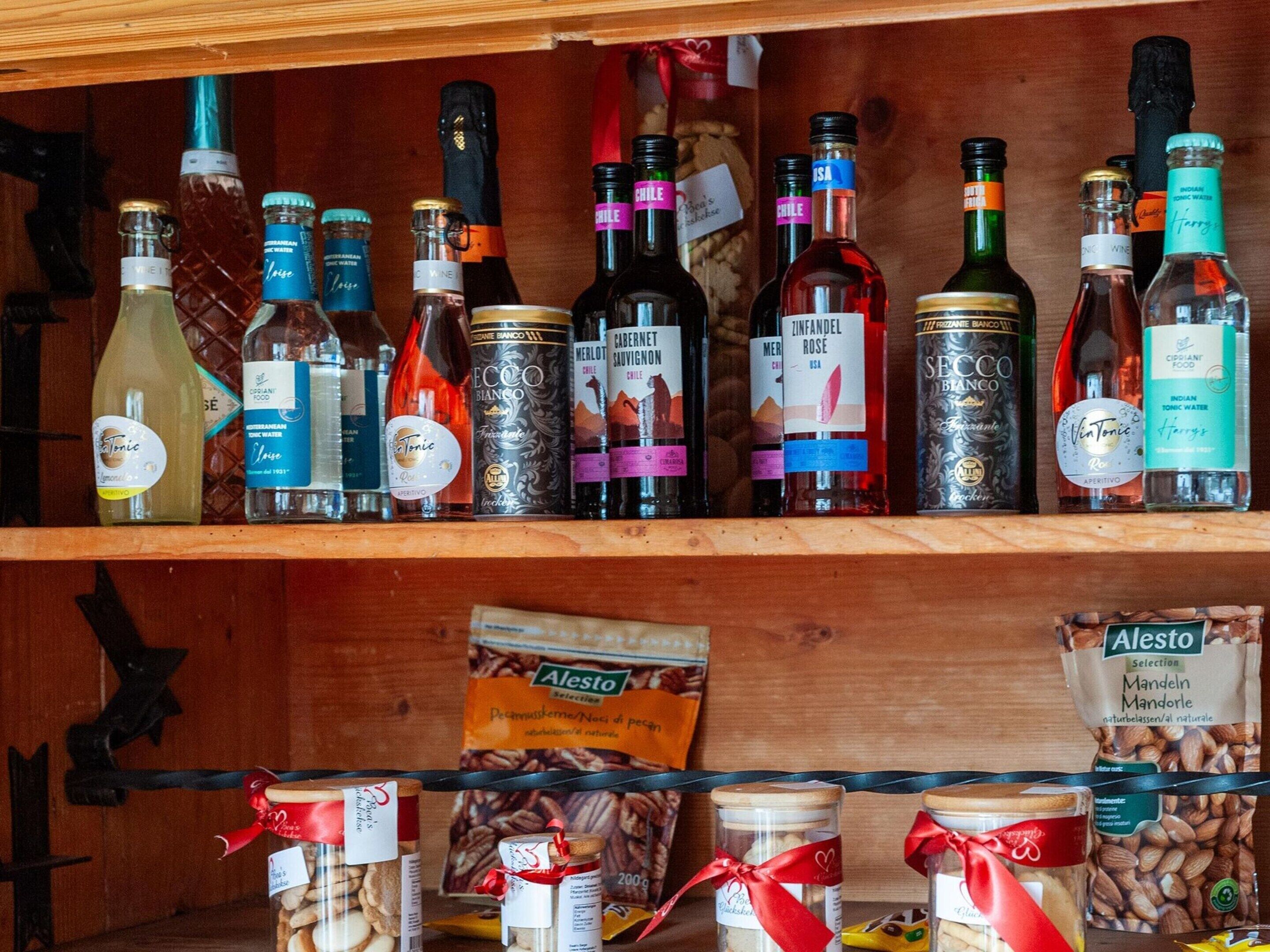 Un estante de madera con diversas botellas de licores y frascos de alimentos.