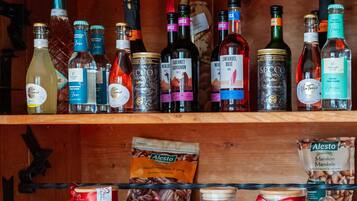 Un estante de madera con diversas botellas de licores y frascos de alimentos.