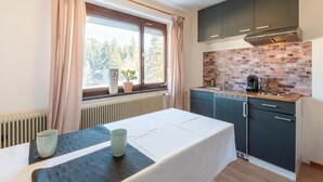 A compact kitchen with a brick backsplash, a window with curtains, and a table with a placemat and a cup. - Idyllic Apartment in Sibratsgfall (Sibratsgfaell)