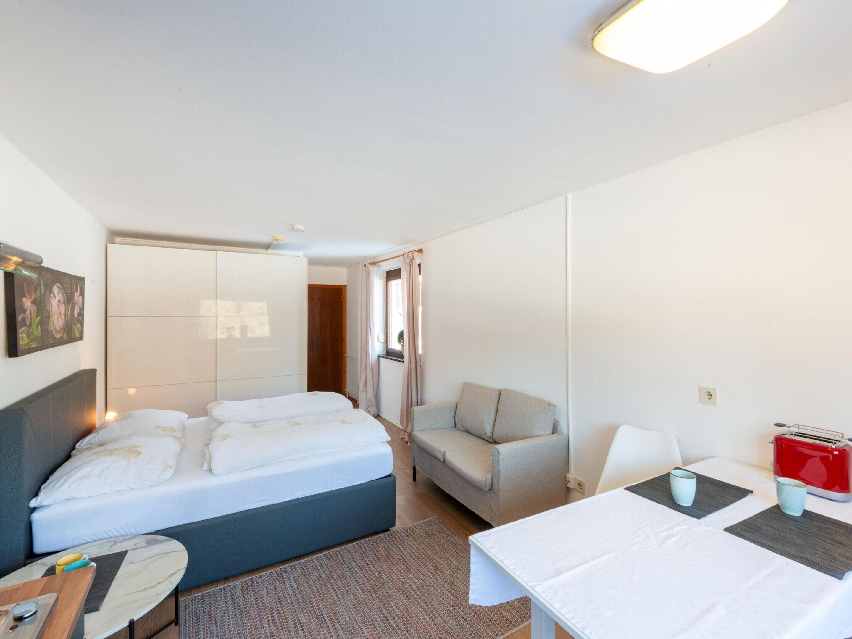 Een hotelkamer met een bed, een sofa, een tafel en een rode toaster.