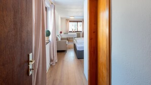 A hallway leading to a bedroom with a window, a radiator, and a small table with a plant. - Idyllic Apartment in Sibratsgfall (Sibratsgfaell)