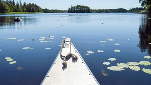 A boat on a calm lake with lily pads and a forest in the background. - 6 Person Holiday Home in Sunne (Sunne)