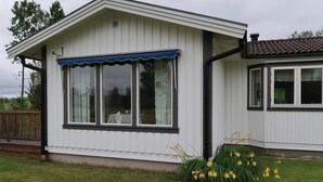 A single-story building with a covered porch and a window with a blue awning. - 6 Person Holiday Home in Sunne (Sunne)