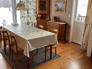 A dining area with a table set for four, wooden chairs, a patterned tablecloth, a lamp, and a cabinet with kitchenware. - 6 Person Holiday Home in Sunne (Sunne)