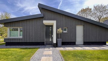 A modern house with a sloped roof, a dark exterior, and a well-maintained lawn.