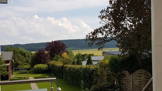 A residential garden with a view of a distant field and hills. - Ferienwohnung in Bissendorf (Bissendorf)