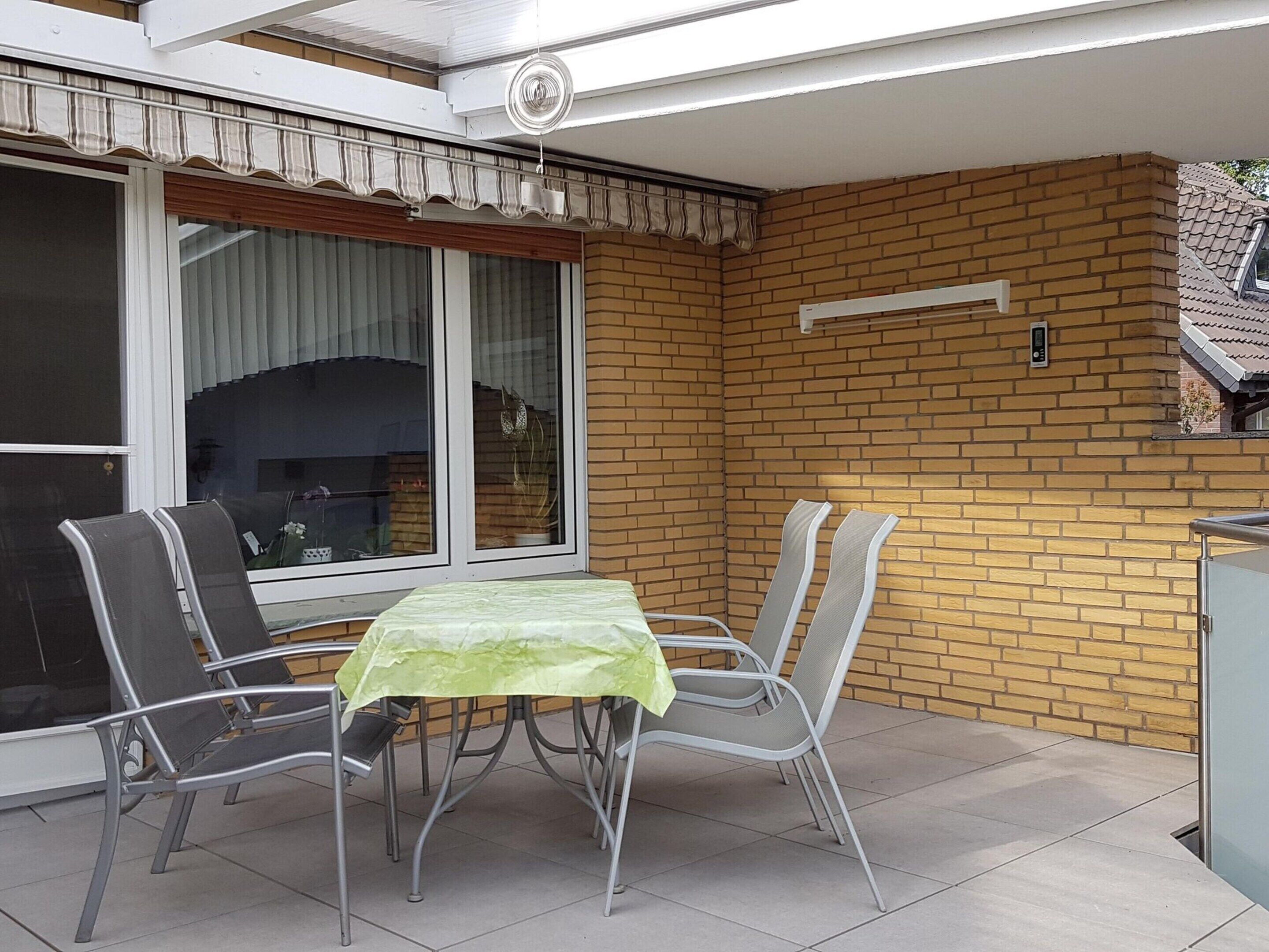 Une terrasse extérieure avec une table et des chaises, une porte-fenêtre coulissante et un mur en briques.