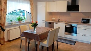A modern kitchen with white cabinets, a built-in oven, and a window with curtains.