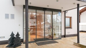 A modern building entrance with a glass door, a metal sculpture, and a paved area. - Apartment in Langenfeld With Infrared Sauna (Laengenfeld)