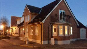 Een twee verdiepingen tellend huis met een bakstenen gevel, een puntige dak en een klein balkon.