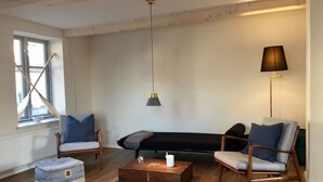 Een moderne woonkamer met een bank, twee fauteuils, een salontafel en een lamp.