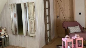 A rustic room with wooden walls, a loft bed, a wooden door, and a small table with pink lanterns. - Holidays in Happiness (Tetenbüll)