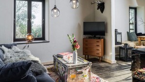 A modern living room with a sofa, a coffee table with magazines, a TV, and a fireplace. - Holidays in Happiness (Tetenbüll)