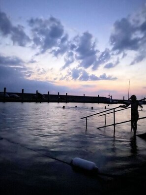 A waterfront with a person walking along a railing. - Holidays in Happiness (Tetenbüll)