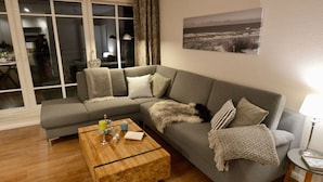 En stue med en grå hjørnesofa, et træbord og en lampe på et sofabord.