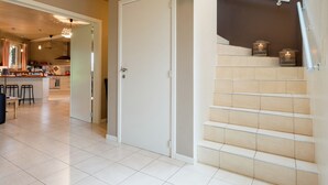 A modern kitchen with a dining area, a staircase, and a door leading to another room. - Luxury Holiday Home With Private Garden (Waimes)
