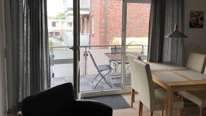 Une chambre moderne avec un balcon, une table à manger et des chaises.