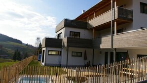 A modern two-story house with a wooden balcony, a swimming pool, and a fenced yard. - Tasteful Apartment in Elzach-yach (Elzach)