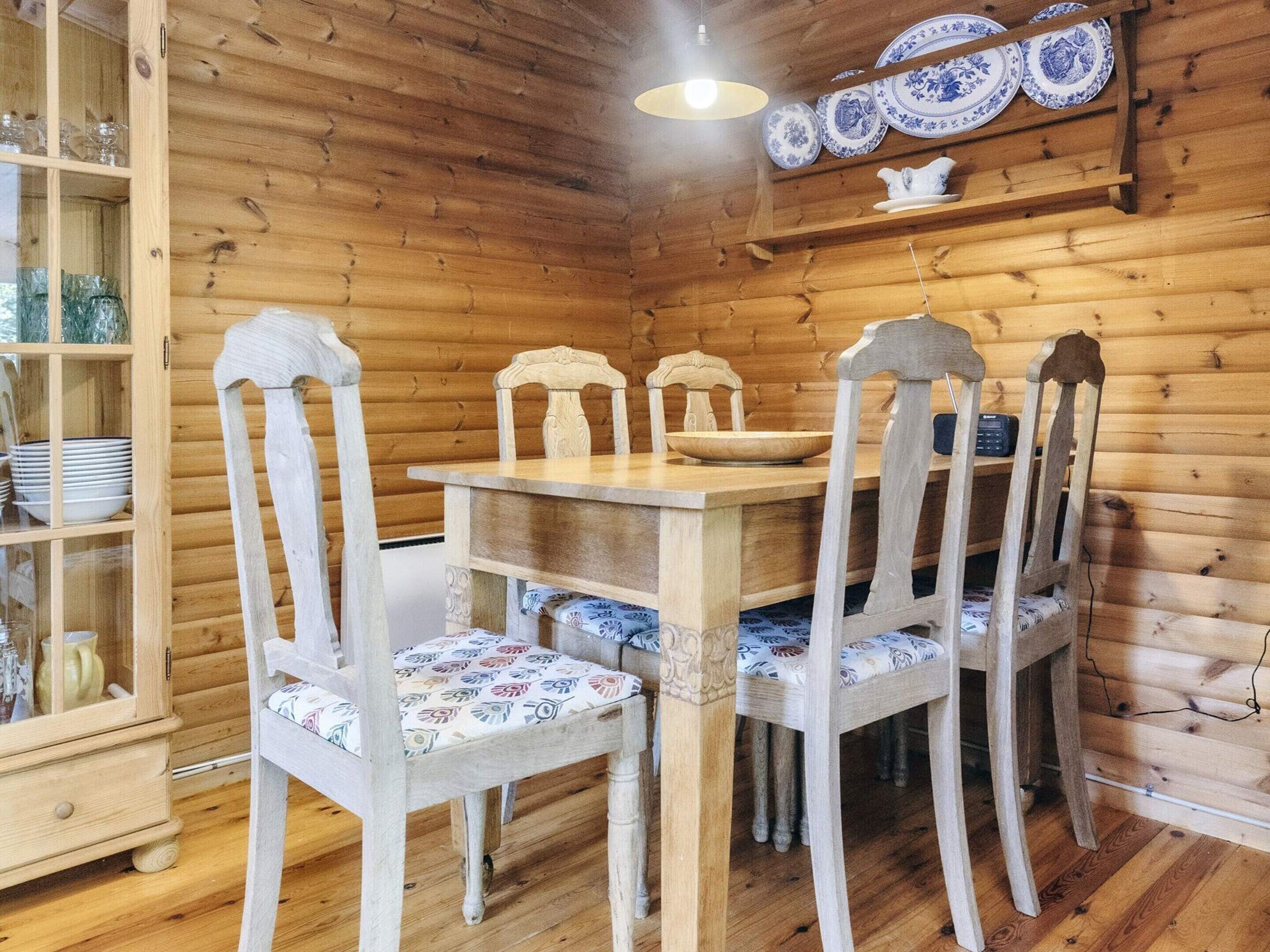 Ein Essbereich aus Holz mit Tisch, Stühlen, einem Schrank mit Geschirr und einer Pendelleuchte.