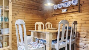 Un coin repas en bois, avec une table et des chaises, un buffet contenant de la vaisselle et un luminaire suspendu.