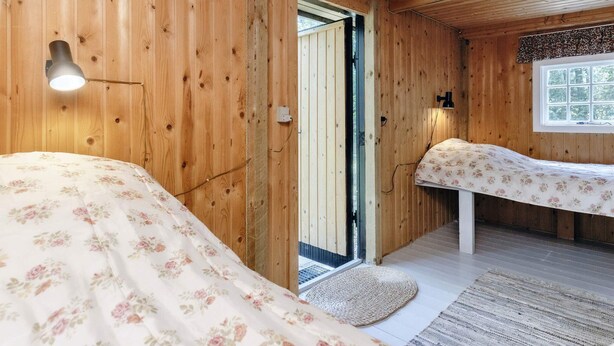 Une pièce en bois avec un lit, un banc et une fenêtre.