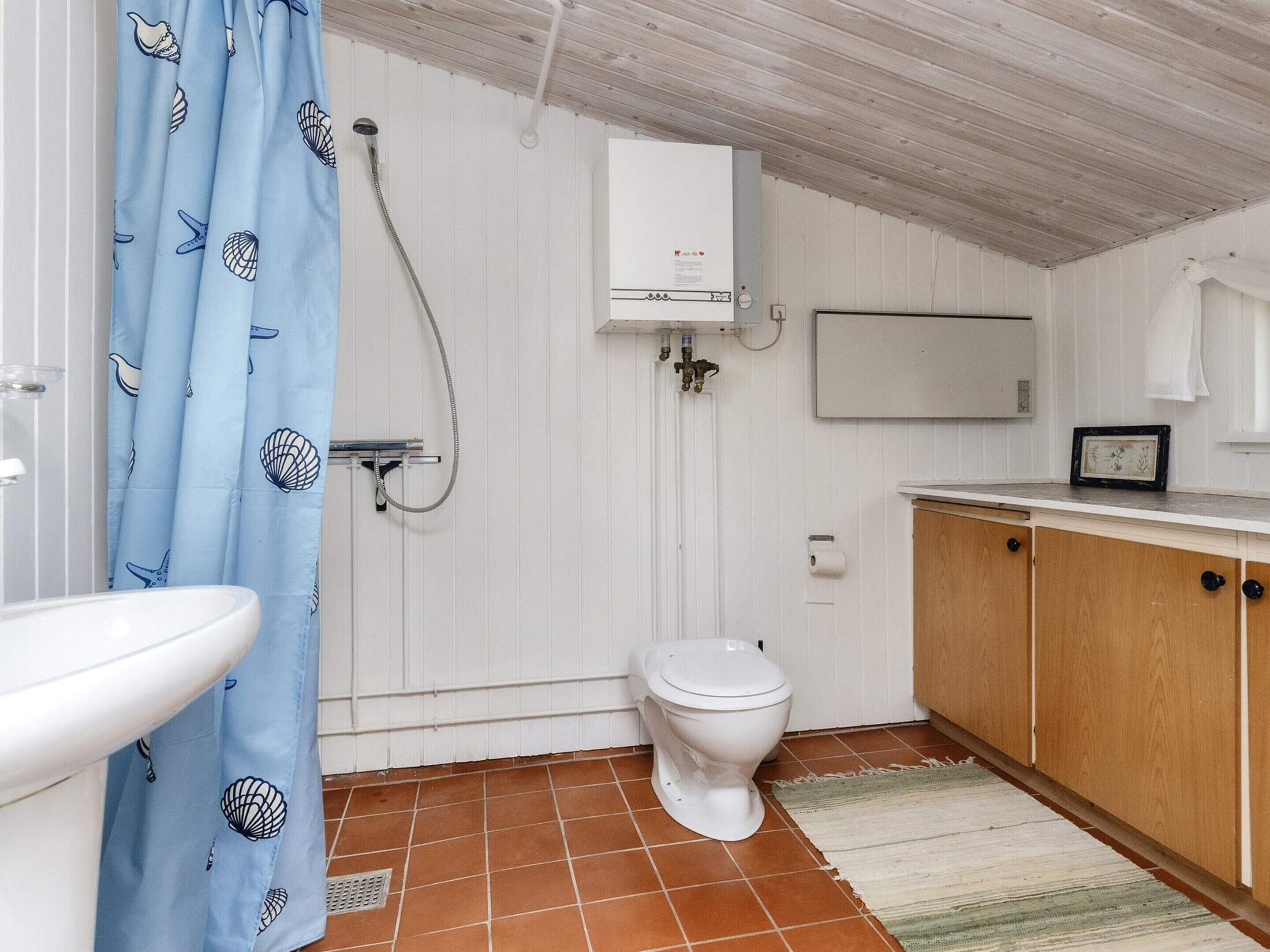 Egy fürdőszoba, amelyben WC, zuhanyzó és mosdókagyló található.