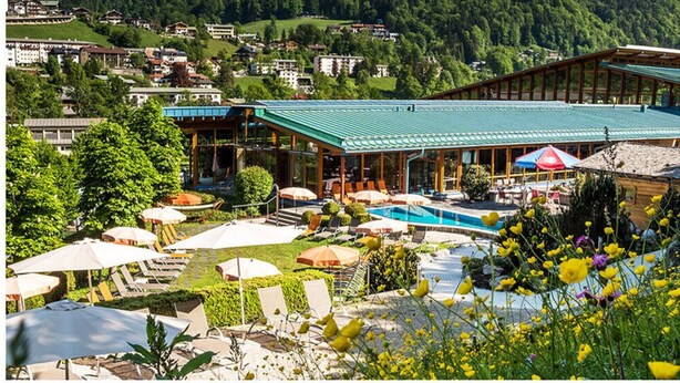 Un resort con piscina, zona de estar al aire libre y vistas a las montañas.