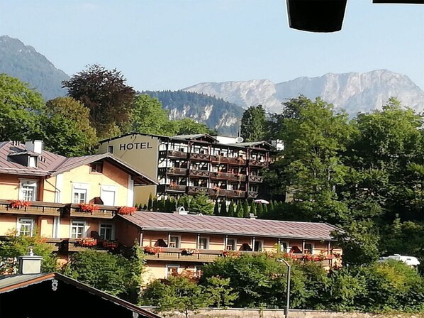 A hotel with multiple floors, balconies with flower boxes, and a mountainous backdrop.