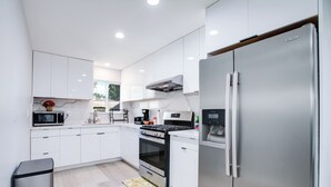 Une cuisine moderne avec des armoires blanches, des appareils en acier inoxydable et un grand réfrigérateur.