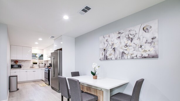 Une cuisine moderne avec des meubles blancs, une table à manger blanche et une chaise grise.