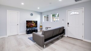 Un salon moderne avec un canapé gris, un téléviseur à écran plat et une porte blanche.