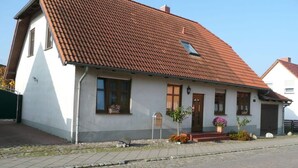 A two-story house with a red-tiled roof, a front porch with flower pots, and a mailbox. - Ostenberg - Near CJD Comfortable Holiday Residence (Garz/Rügen)