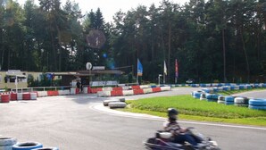 A go-kart track with a single go-kart in motion, surrounded by tire barriers and a wooded area in the background. - Ostenberg - Near CJD Comfortable Holiday Residence (Garz/Rügen)