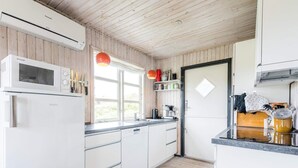 A modern kitchen with white cabinets, a built-in microwave, and a stainless steel refrigerator. - 6 Person Holiday Home in Henne (Henne)