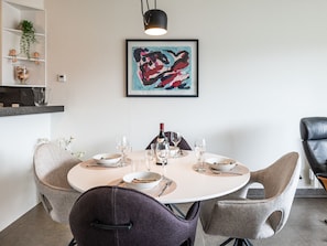 A dining area with a round table, two chairs, a bottle, and glasses. - Luxury Apartment in the Center of Koksijde (Koksijde)
