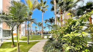 A pathway flanked by palm trees and lush greenery, leading to a building with a modern architectural style. - Sunny Escape in Playa Motril (Motril)