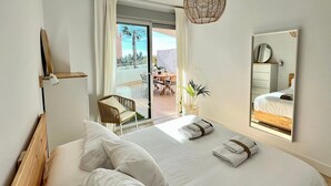 A modern hotel room with a large bed, a balcony with a table and chairs, and a view of palm trees. - Sunny Escape in Playa Motril (Motril)
