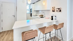 A modern kitchen with white cabinetry, a large island with bar stools, and pendant lighting. - Sunny Escape in Playa Motril (Motril)
