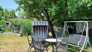 Une terrasse avec une table et des chaises, un auvent à rayures et une balançoire.