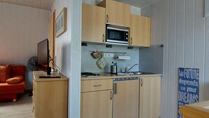 Une cuisine de taille réduite, dotée de meubles en bois, d’un four à micro-ondes, d’un évier et d’une cuisinière.
