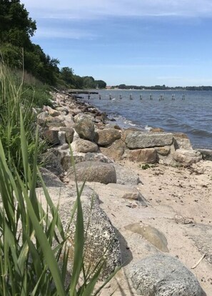 A rocky shoreline with a clear view of the water and distant land. - Hein Muck Modern Retreat (Gluecksburg)